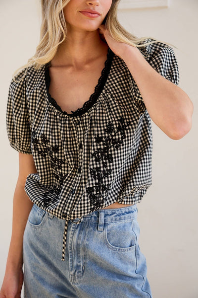 VIDA MOULIN black and white gingham blouse with floral embroidery, puff sleeves, and scoop neckline.
