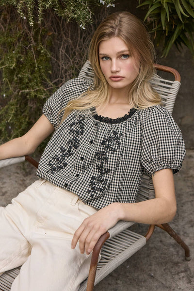 VIDA MOULIN black and white gingham blouse with floral embroidery, puff sleeves, and scoop neckline.