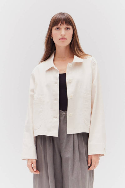 VIDA MOULIN cream twill cotton jacket with button closure and two chest pockets. Model wears a black top and grey trousers.