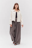 VIDA MOULIN cream twill cotton jacket with a relaxed fit, collared neckline, and button front. Model wears it with wide-leg grey pants.